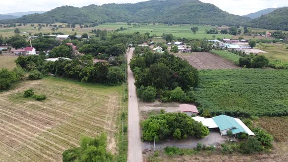 Drone video of a road in a rural village in a mountainous area with green trees in Thailand.