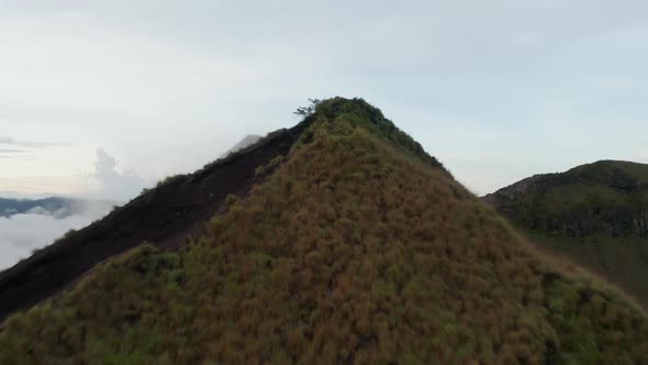 Ascending Aerial Dolly Shot Flying Past the Mountain Peak of a Mount Batur in Bali Covered in a alt