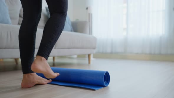 Close up of sportswoman feet roll out exercise mat to start work out by doing yoga stretching body. alt