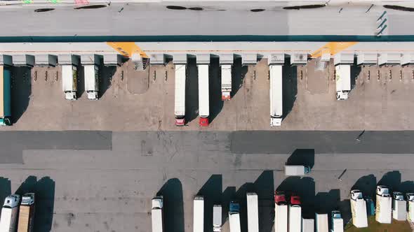 Lorry Drives Past Trucks Standing Near Huge Warehouse Ramps alt