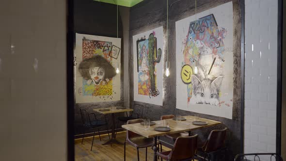 Pushin of Colorful Artwork on Walls Over Tables in Cozy Restaurant alt
