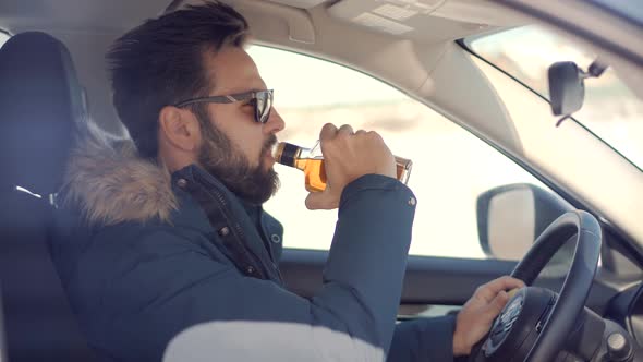 Drunken Driving Risk Car Accident.Man Holding Alcohol Bottle In Car. Dangerous On Road Drunk Driving alt