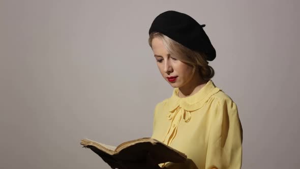 Stylish woman with vintage book on grey background