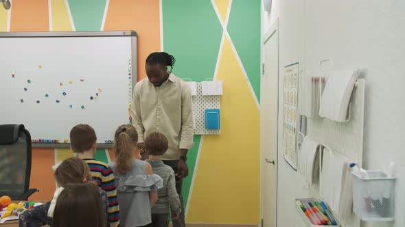 An African American Teacher Teaches a Group of Children 1012 Years Old Studying Animals and Fruits alt
