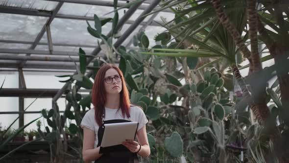 Work in a Greenhouse, Woman Takes Notes in a Tablet for Papers alt