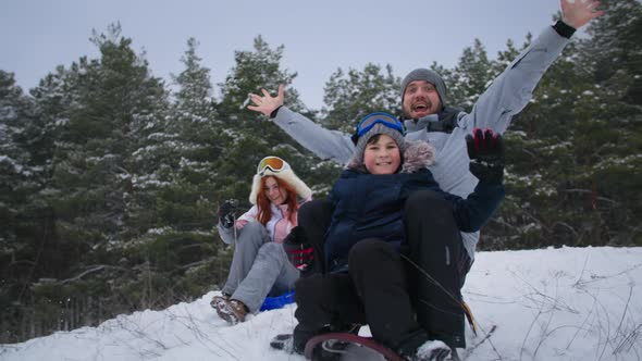 Family Weekend Happy Father with Sons and Wife Have Fun Sledding in Winter Forest in Snowy Weather