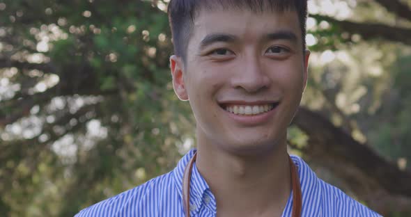 Close up Happy Smiling Face Of Handsome Young Asian Man In The Park alt
