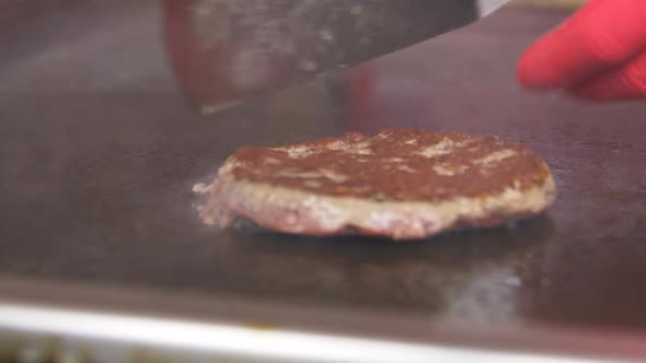 Closeup Side View Hands in Red Gloves Turn Over Cutlet alt