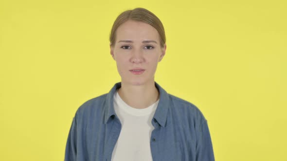 Serious Young Woman Looking at the Camera on Yellow Background alt