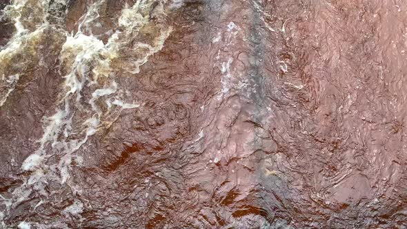 River flowing through grass in rain, slow panning shot below to above alt