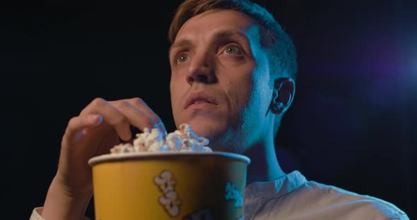 Man watching a horror movie at the cinema and eating popcorn