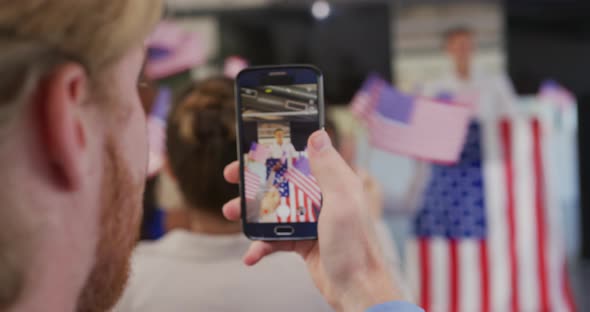 Audience member filming political rally with smartphone alt