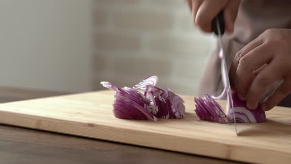 Close up of chef hands slicing red onion with knife