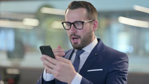 Disappointed Businessman Reacting To Loss on Smartphone alt