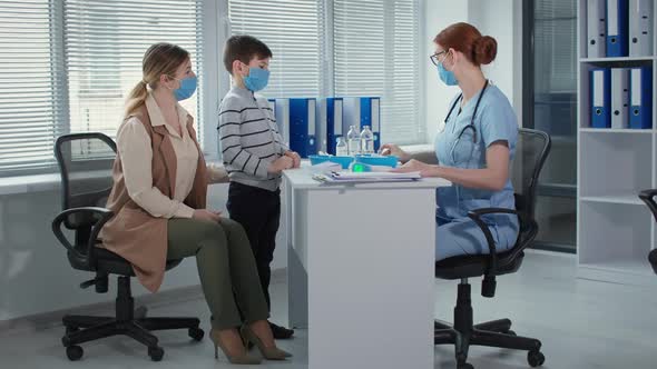 Doctor in Blue Uniform with Stethoscope Tells the Boy and His Mom About the Vaccine Family and