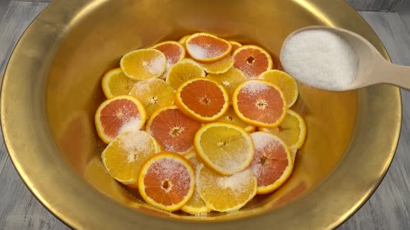 Preparation of orange jam, orange slices is sprinkling with sugar in a copper basin