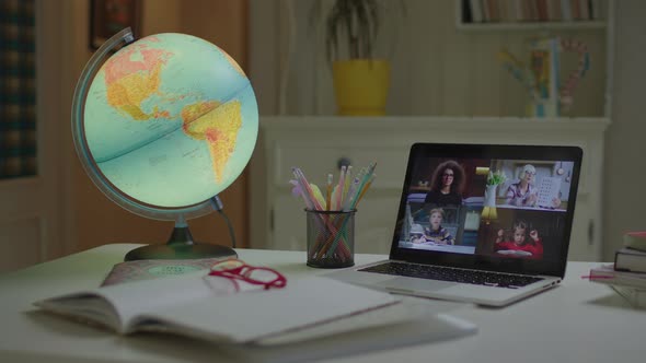 Laptop with Talking Online Teacher and Pupils on the Empty Desk with Lighting Earth Globe alt