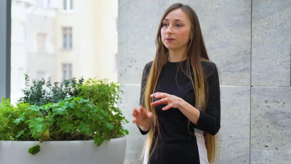 Young Woman with Long Hair Actively Gesturing While Giving a Stand Up Talk alt