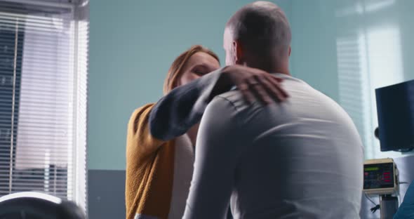 Woman Supporting Man in Hospital Ward alt