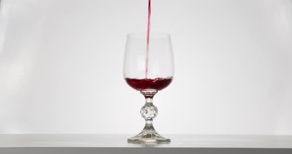 Close-up Shot, The Red Wine Is Pouring Into a Glass. White Background alt