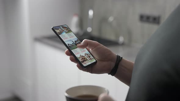 A Man Chooses a New Home for Himself Through an Application on a Smartphone alt