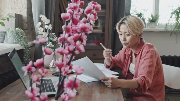 Asian Woman Doing Paperwork at Home alt