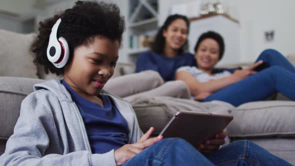 Mixed race girl using a digital tablet with headphones on alt