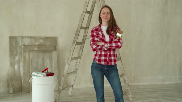 Woman Paints Walls at Home Holds Paint Brush alt