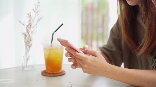 Young woman with drinks using mobile phone and relaxing in cafe, Modern lifestyle