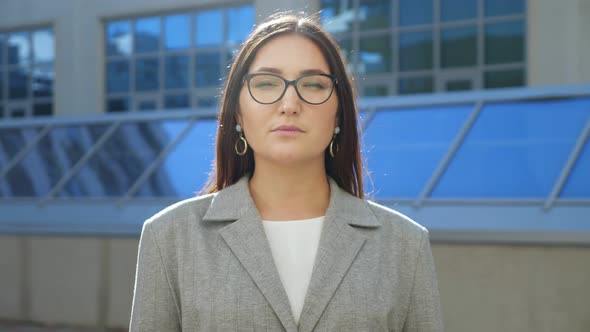 Young Woman in Suit and Glasses Smiling at Camera on the Street alt