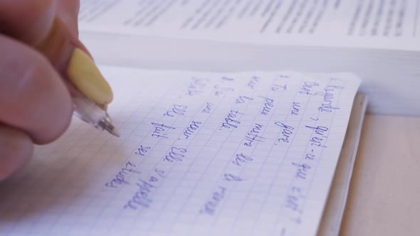 Female Hand Making Notes in Notebook While Studying French alt