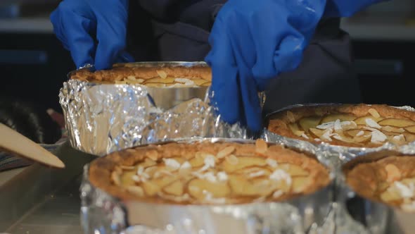 A Bluegloved Pastry Baker Pulls One of Several Hot Baked Pear and Cheese Pie From a Baking Sheet