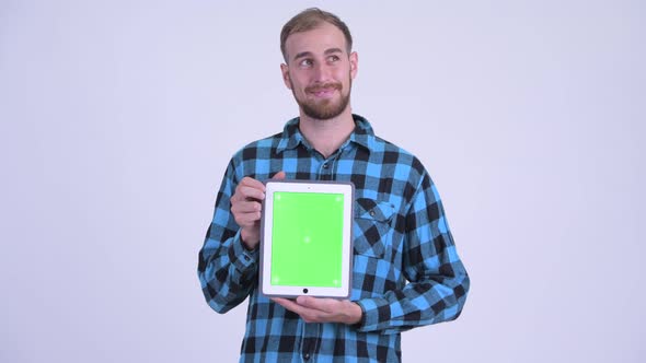 Happy Bearded Hipster Man Thinking While Showing Digital Tablet alt
