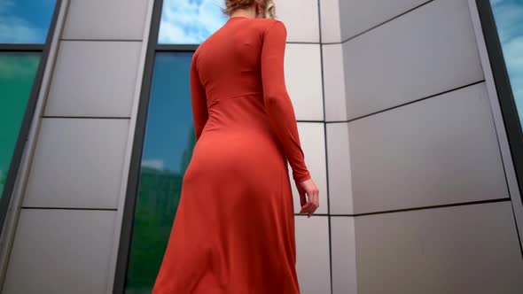 the Blonde in the Red Dress Goes To the Wall and Turns. the Camera Moves From Bottom To Top alt