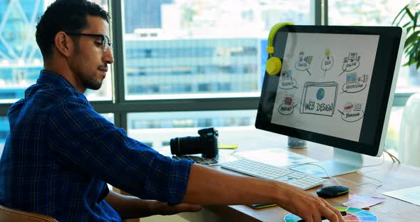 Male graphic designer working over graphic tablet at his desk alt