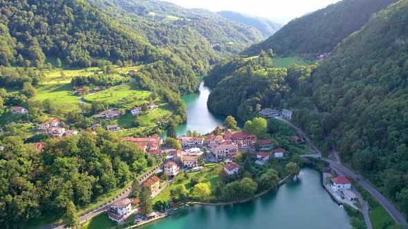 Aerial view of a peaceful town surrounded by green mountains and a beautiful river alt
