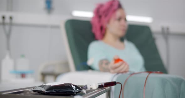 Young Woman in Headphones Listening to Music Lying on Couch and Donating Blood alt