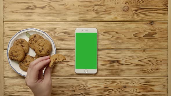 Unrecognizable Person Drinking Coffee and Eating Cookies Near Smartphone alt