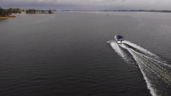 Speedboat crossing the drone shot while proceeding on full speed on a fairway at wide streched lake alt