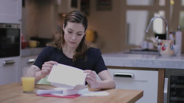 Young adult woman opening bills at home