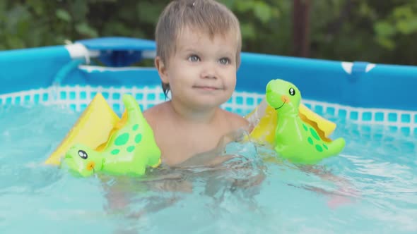 Kid in Oversleeves Swims in the Pool in the Yard alt
