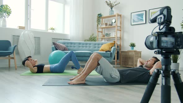 Girl and Guy Bloggers Working Out and Recording Video for Internet Blog Enjoying Activity alt