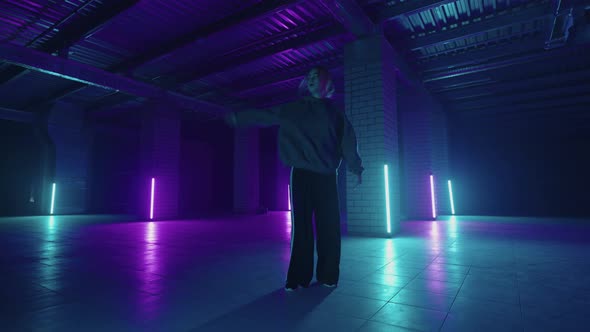 A Steel Woman Dances Hiphop Freestyle in a Modern Style in a Hall with Neon Light in Purple Blue alt