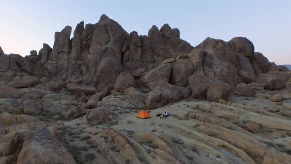 Aerial shot of a young man backpacker camping with his dog in a mountainous desert. alt