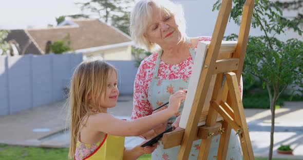Granddaughter and grandmother painting on canvas 4k alt