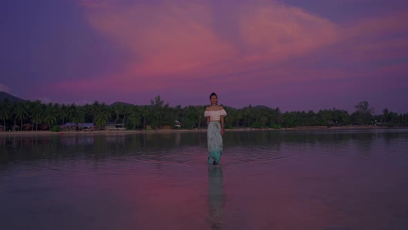 Young Asian Woman Walking Alone in the Sea at Beautiful Sunset Thailand alt