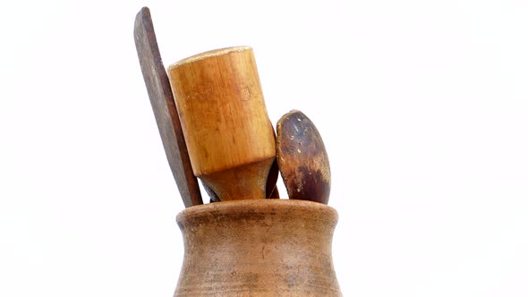 Clay pot with wooden utensils on a white background.