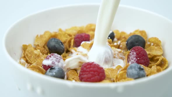 Pouring Milk On Corn Flakes With Raspberries And Blueberries