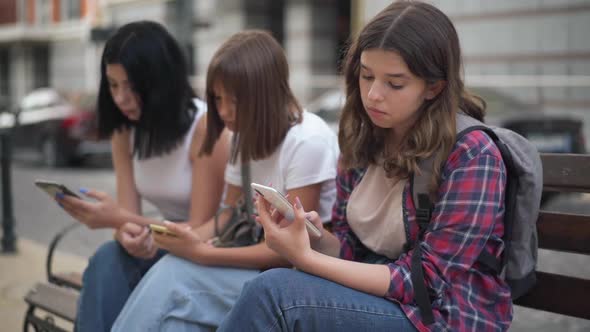 Bored Caucasian Teenage Girl Yawning Sitting on City Street with College Groupmates Surfing Social alt