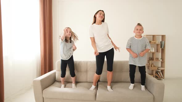 Mom Plays with the Children They Jump on the Couch Have Fun and Hug alt